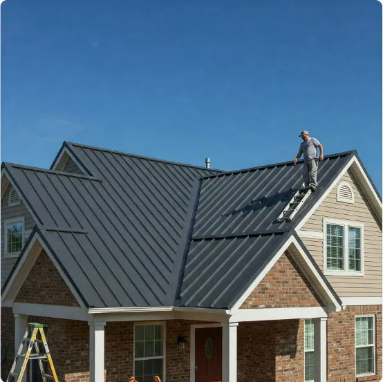 Worker installing a metal roof on a two-story house using a ladder under a clear blue sky.