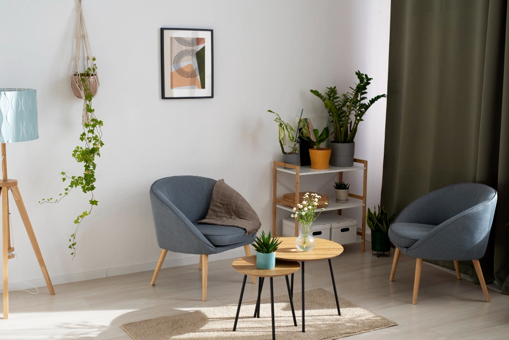 Cozy living room with gray chairs, round wooden table, and plants highlighting small drawing room remodeling.