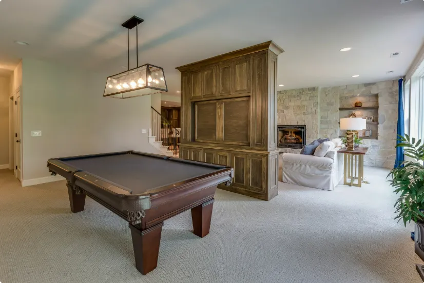 Stylish recreation room with billiards table, wooden cabinetry, fireplace, and seating, showcasing customized room addition.