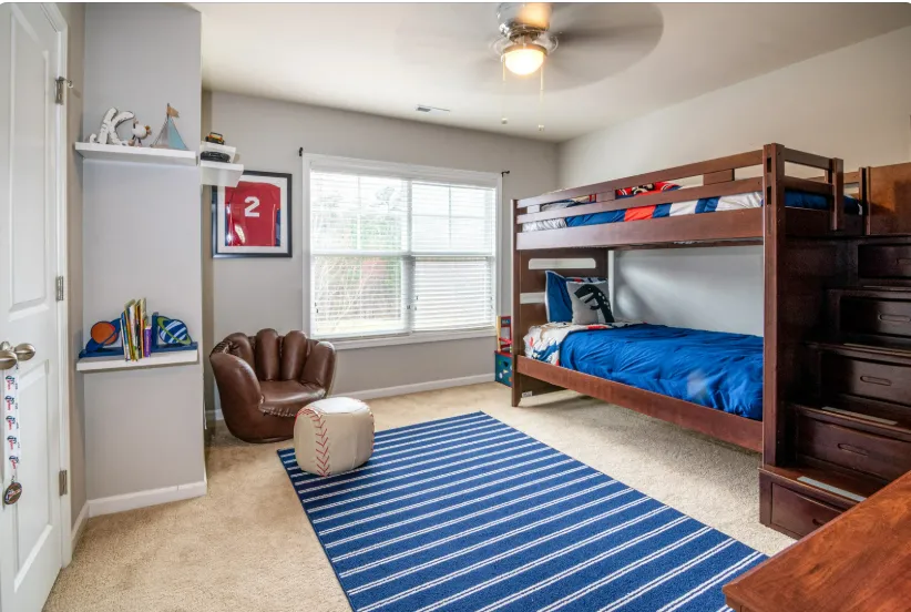 Cozy kids’ room with bunk bed, bean bag, striped rug, and sports decor, designed with custom floor plan layout.