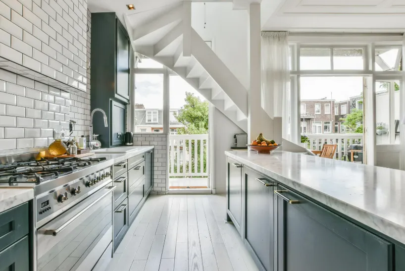 Bright modern kitchen with sleek design, white cabinets, and stairs to sunny balcony, ideal for kitchen and bathroom addition.