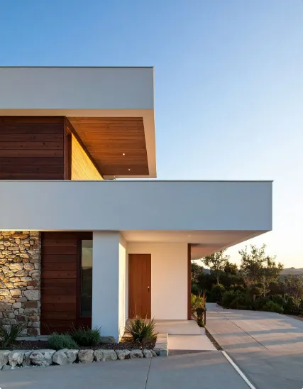 Modern home with wood, stone, and white siding, showcasing stylish exterior finishes under a clear blue sky.