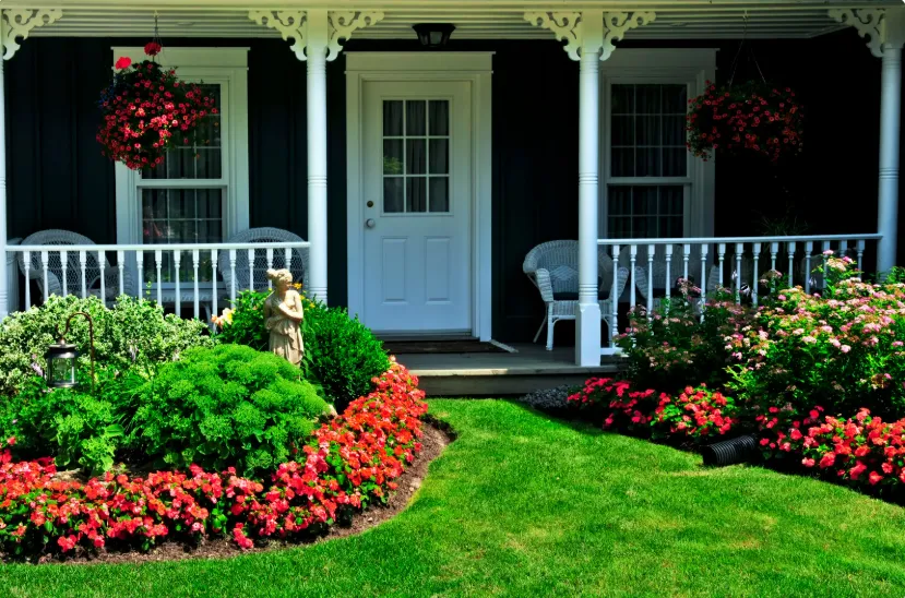 Front porch with vibrant flowers, lush greenery, and stylish furniture, offering inviting home landscaping ideas.