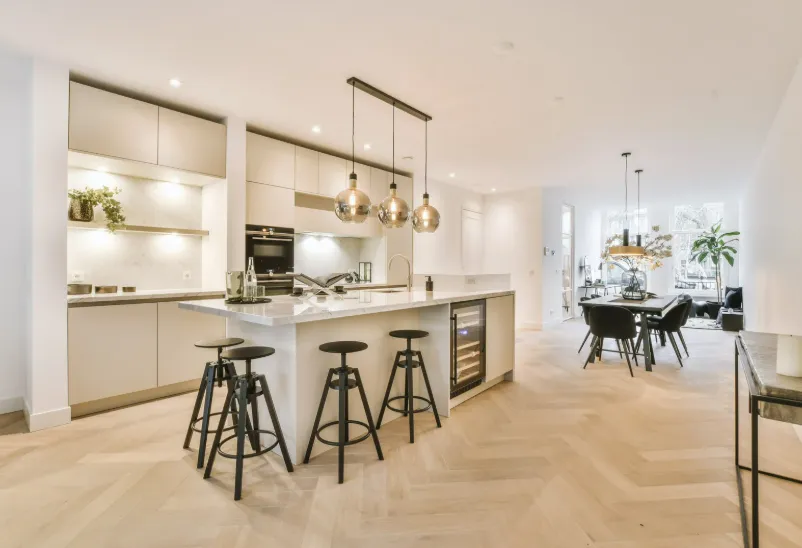 Modern kitchen with large island, bar stools, pendant lights, and sleek cabinets, perfect for kitchen and dining remodeling.