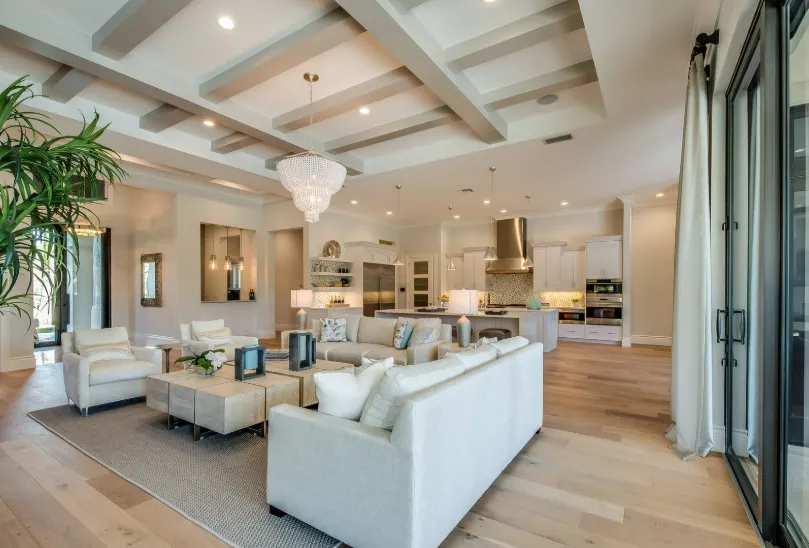 Spacious modern living room with coffered ceiling, chandelier, and stylish furniture for luxury living room remodeling.