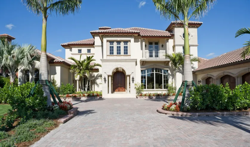 Two-story Mediterranean mansion with tiled roof, large windows, and tropical landscaping showcasing outdoor remodeling.