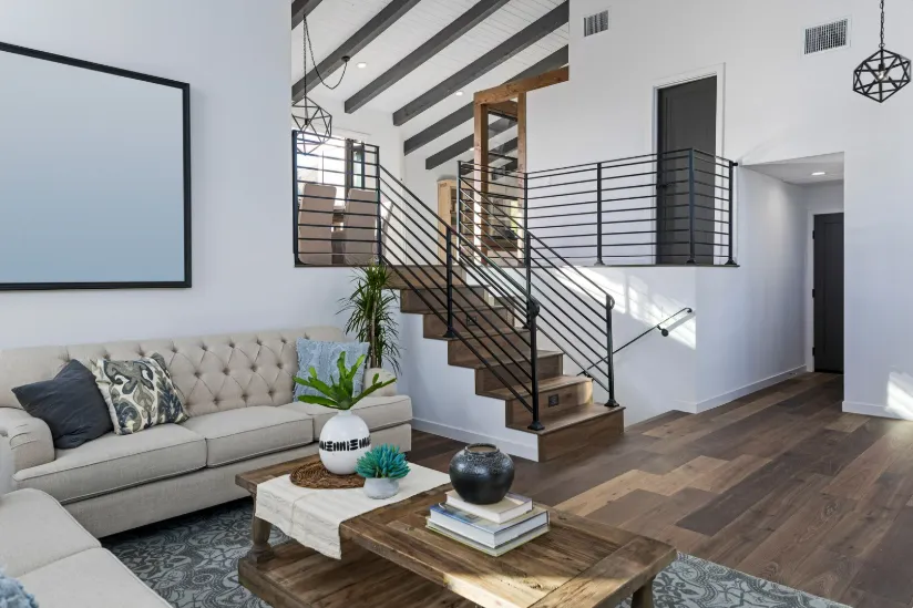 Modern living room with tufted sofa, coffee table, and sleek staircase, highlighting organized living room remodeling.