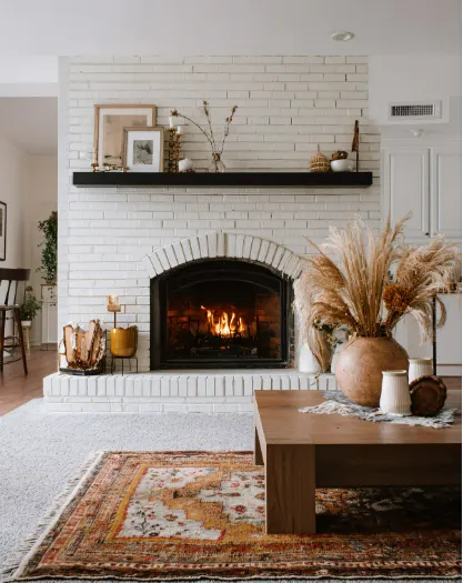 Cozy living room with brick fireplace, wooden coffee table, and plants, showcasing stylish fireplace remodeling.