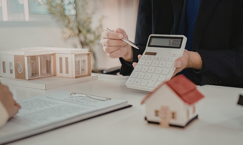 A professional contractor holding a calculator next to home models and a contract, illustrating flooring installation costs and budget planning.